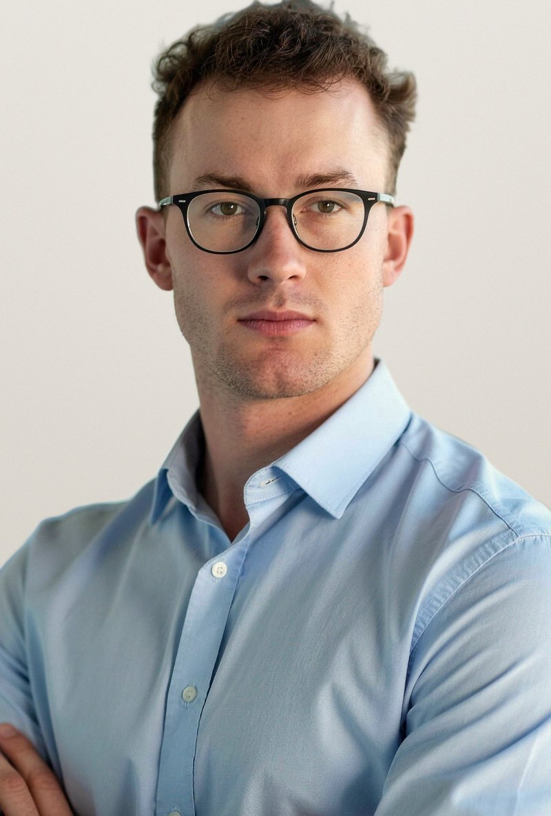 Portrait de Lucien, en chemise bleu clair et lunettes.